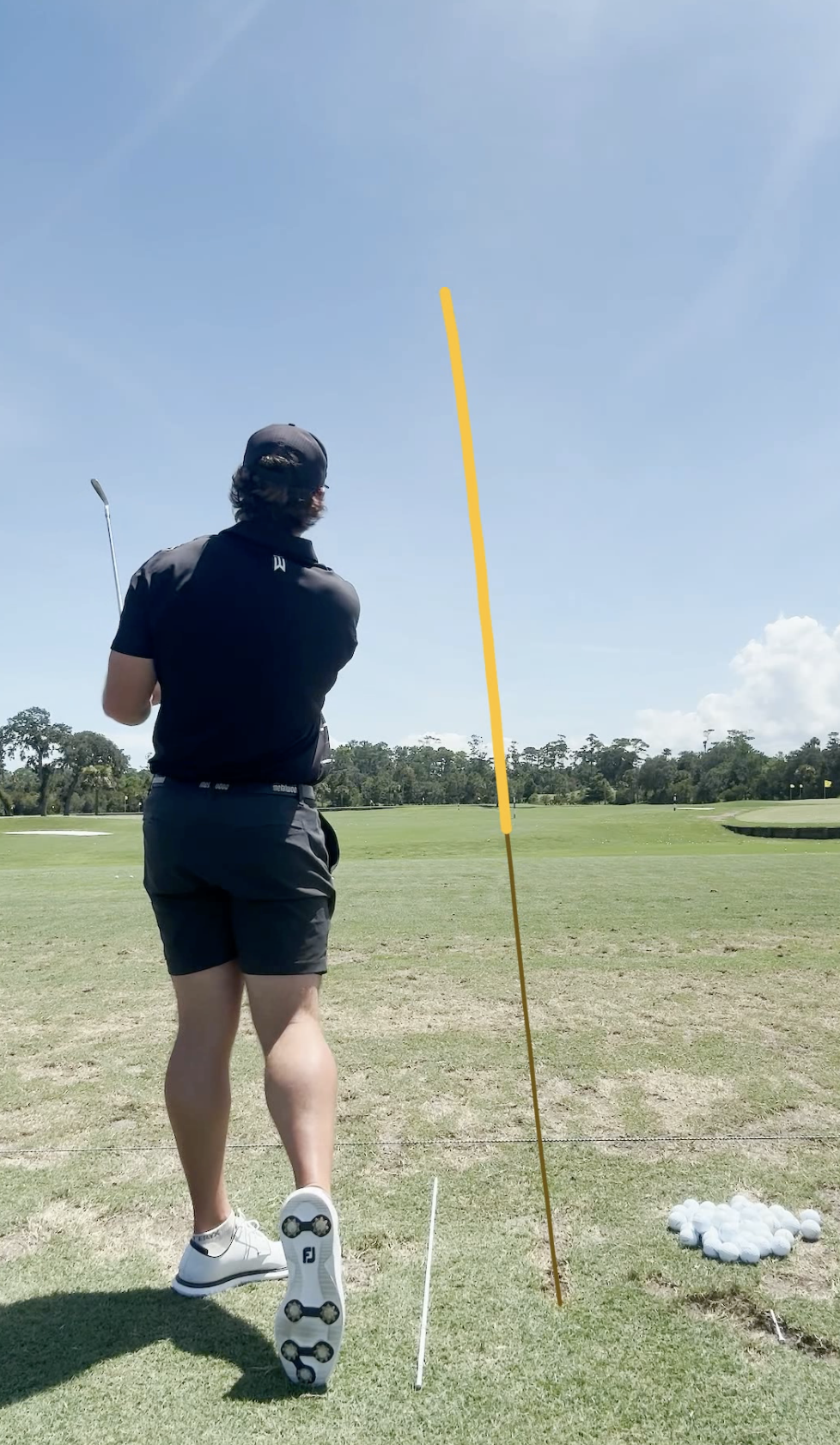 Camera and alignment-pole setup on the range, with the camera positioned behind the hitting area.